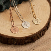 Close-up of engraved name around silver birthday flower pendant